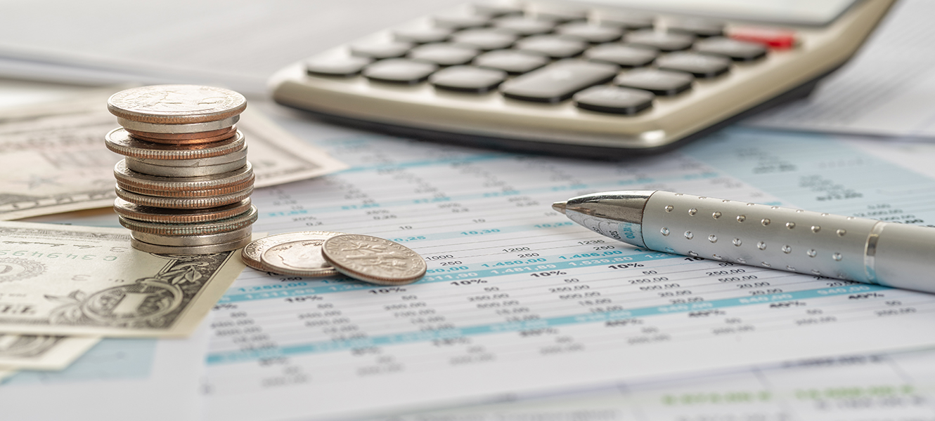 calculator, stack of coins, pen, and paper with budget